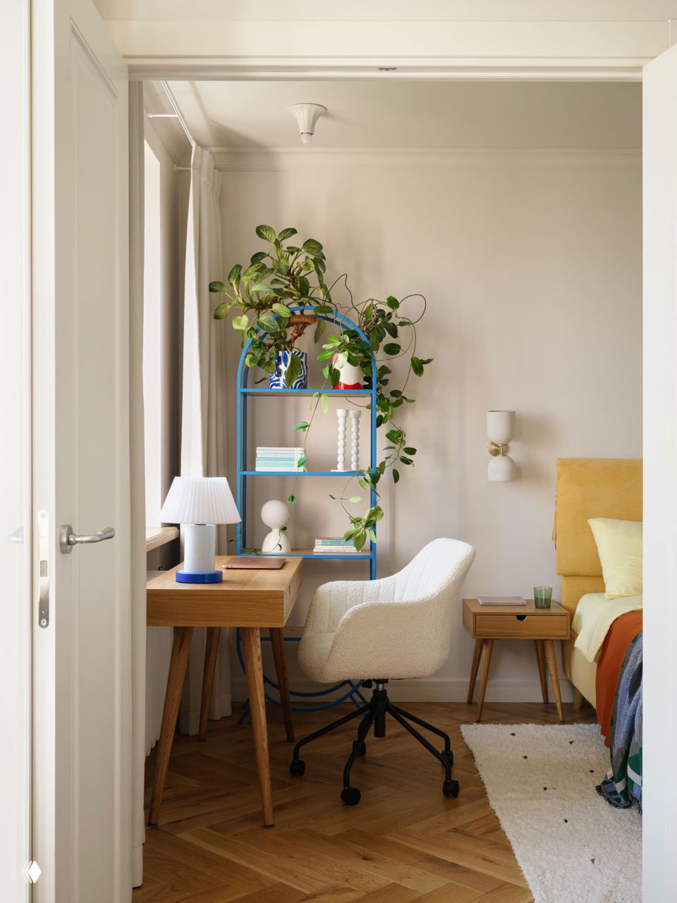 Спальня с жёлтым изголовьем кровати, оранжевым пледом и текстильными акцентами; тёплые натуральные тона и настенное панно создают характер помещения.