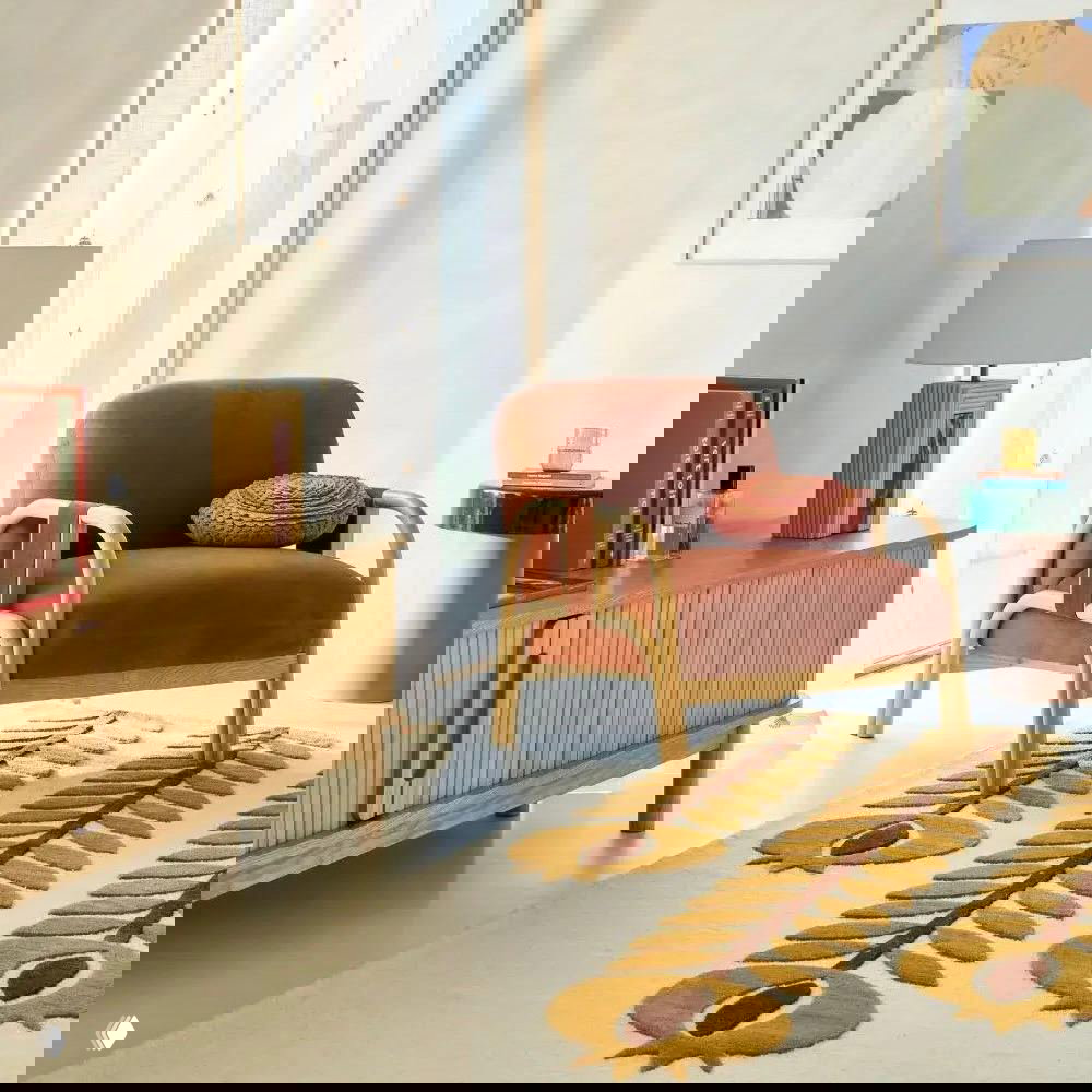 Кресло терракотового оттенка с деревянным каркасом, комод светлого дерева и ковёр с жёлто-коричневыми мотивами в уютном интерьере.