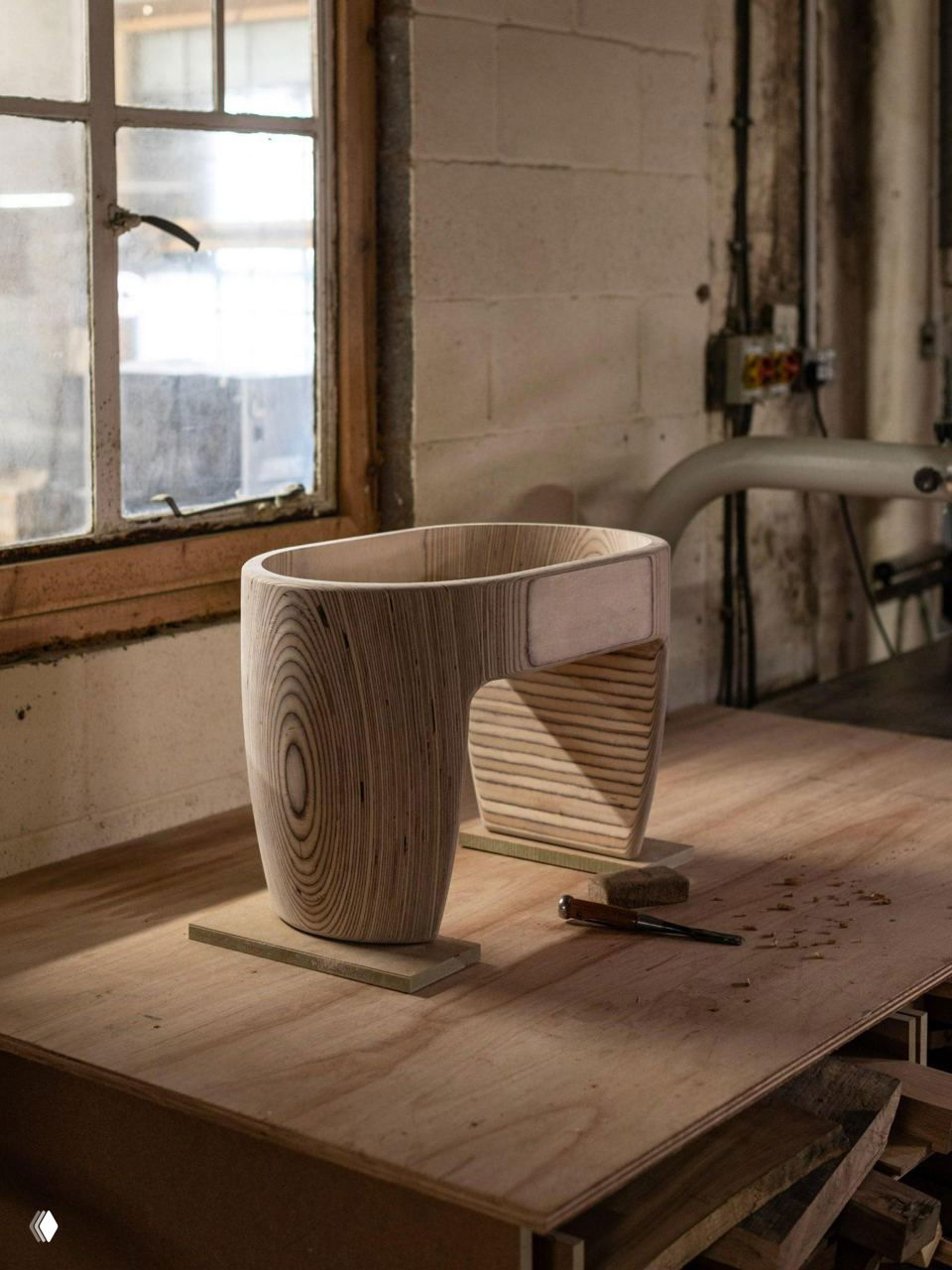 Табурет и заготовки из березы в мастерской: слоистая структура древесины и инструменты, подчёркивающие токарную обработку деталей.