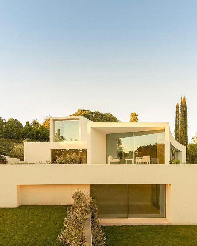 Фасадная перспектива Villa Lago: террасы и большие панорамные окна, за которыми виднеется зелёная растительность участка и бункер гольф-поля вдалеке.