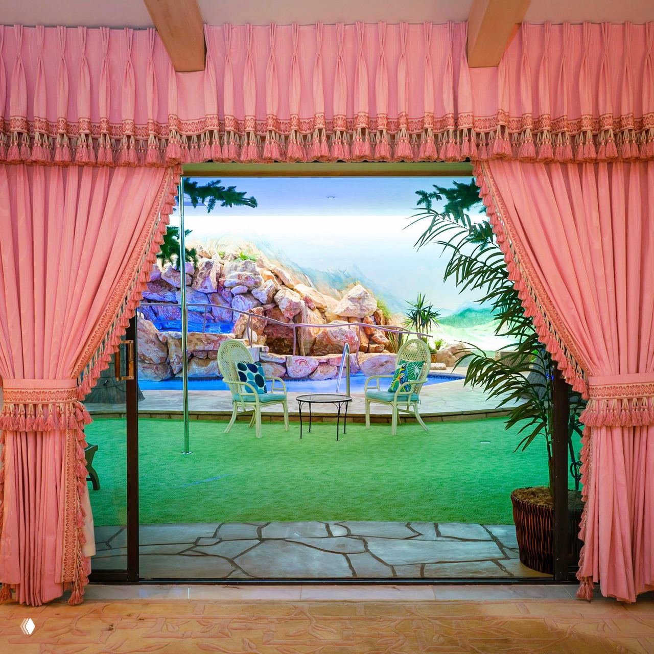 Проход к внутреннему дворику бункера: тяжёлые розовые гардины, искусственная лужайка и территория у бассейна с декоративными камнями.