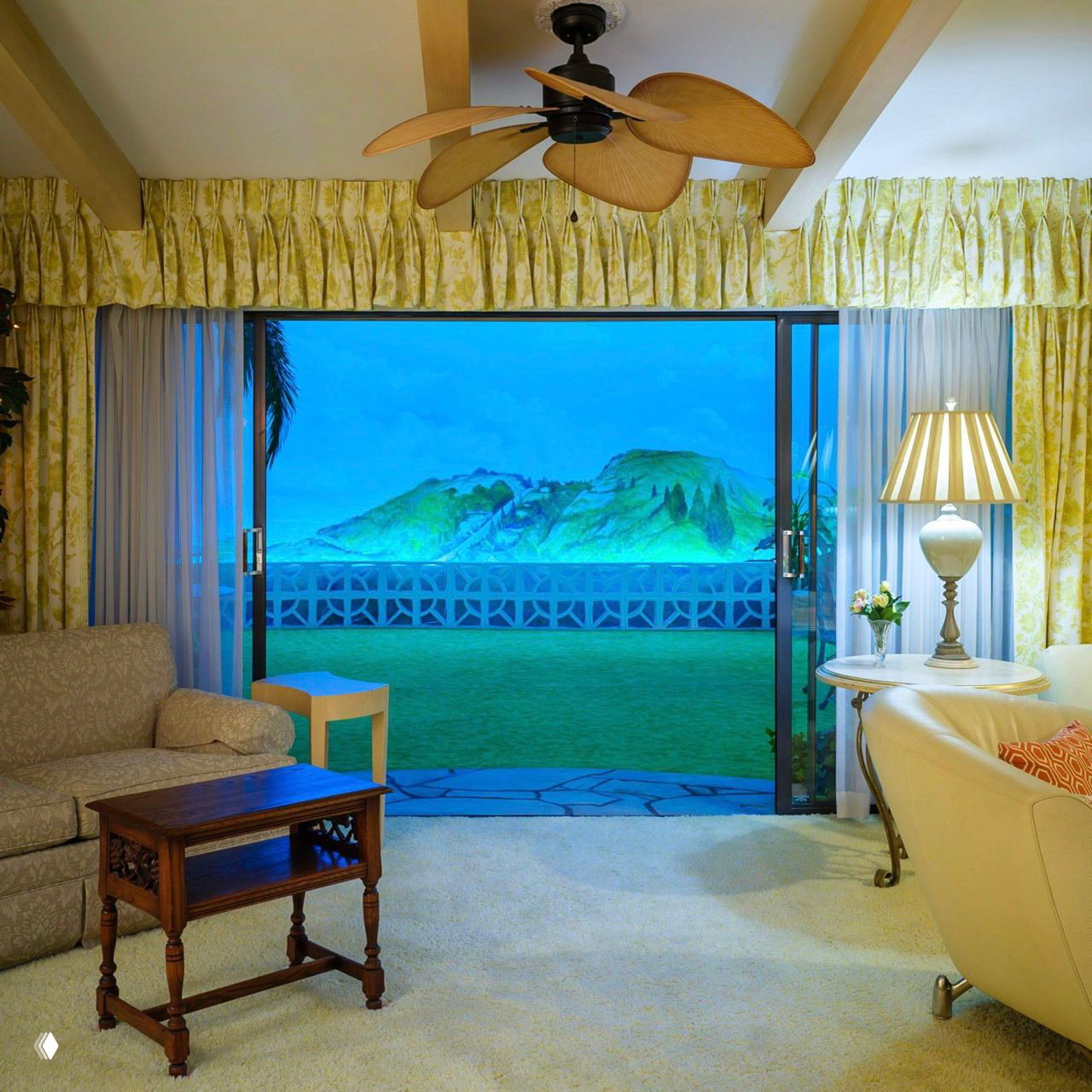 Гостиная бункера с потолочным вентилятором, мягкой мебелью и раздвижной панорамой: пастельные шторы и вид, стилизованный под открытый пейзаж.