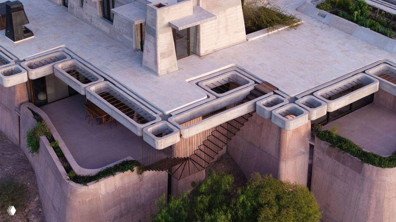 Крупный план угловых бетонных элементов: рельефная фактура поверхности, округлые формы цоколей и встроенные террасы, видны лестницы и перепады уровней.