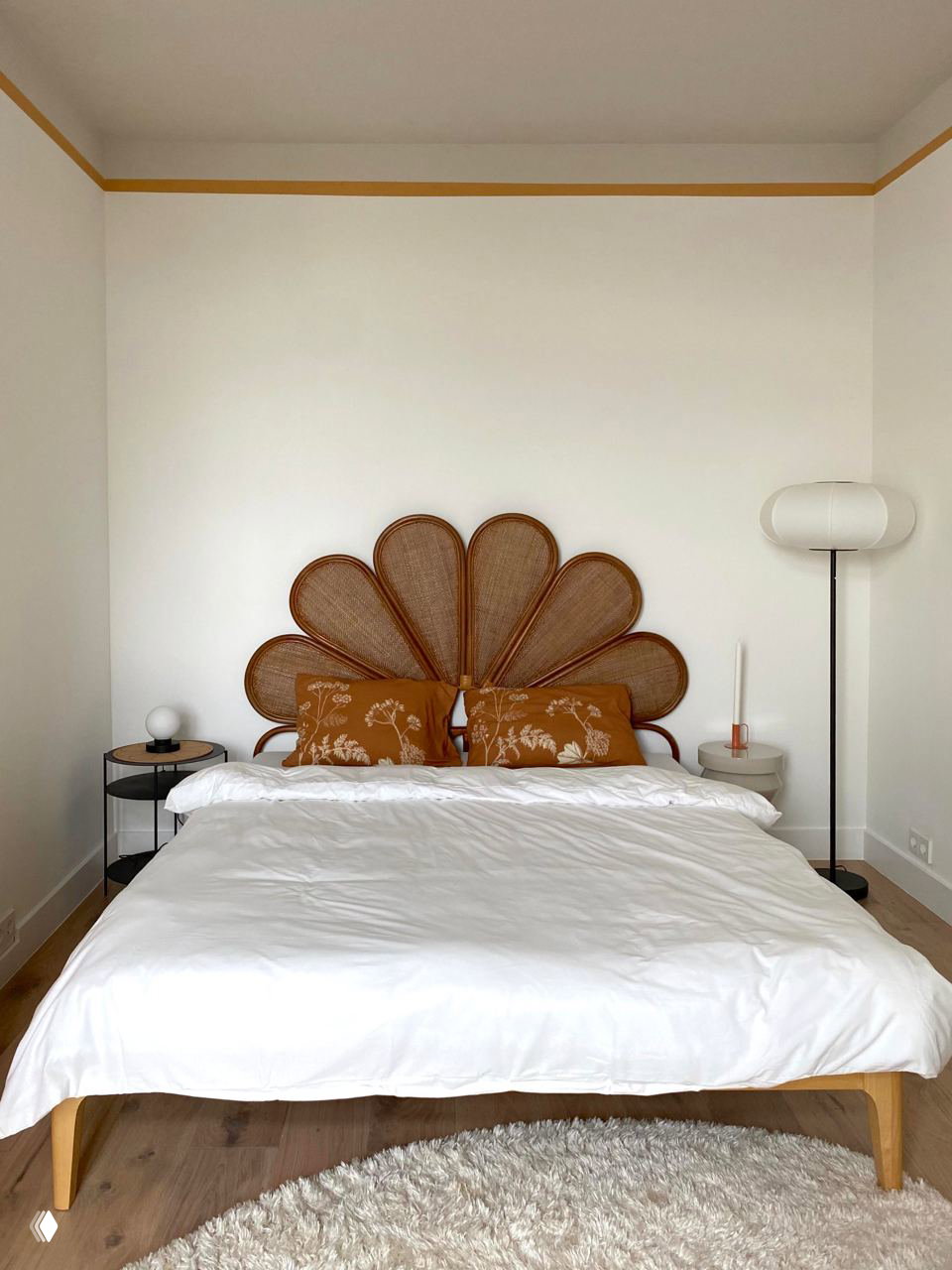 Спальня с эффектным изголовьем в форме лепестков из плетёного материала, светлый текстиль и округлый пушистый ковер на полу.