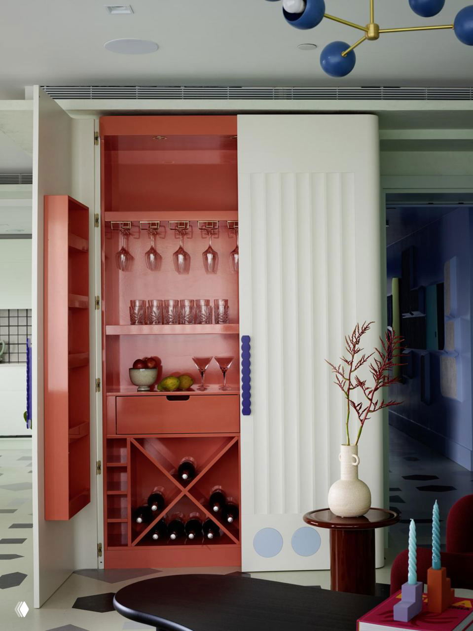 Встроенный вертикальный шкаф-бар кораллового цвета с отделениями для бутылок и полками для бокалов — компактный вариант хранения напитков на кухне.