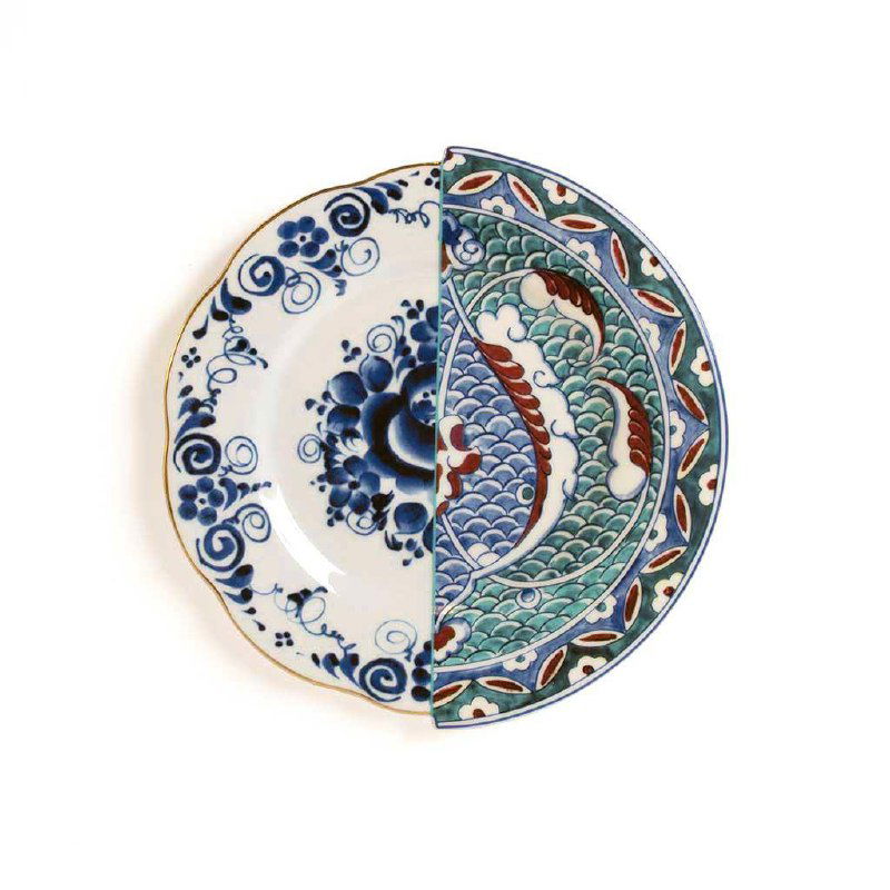 Тарелка, разделённая по вертикали: слева классическая синяя роспись, справа — волнообразные зелёно-голубые узоры в стиле изника, подчёркнутые золотой кантовкой.