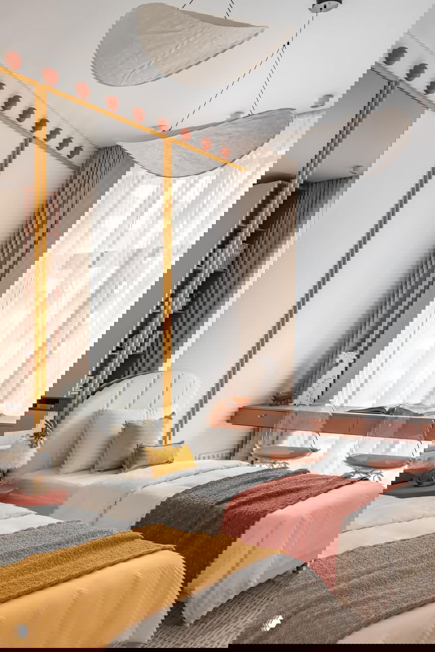 Детская или гостевая комната: две односпальные кровати, текстиль в оранжевых и горчичных оттенках, прозрачные кресла у рабочего столика и большие окна.