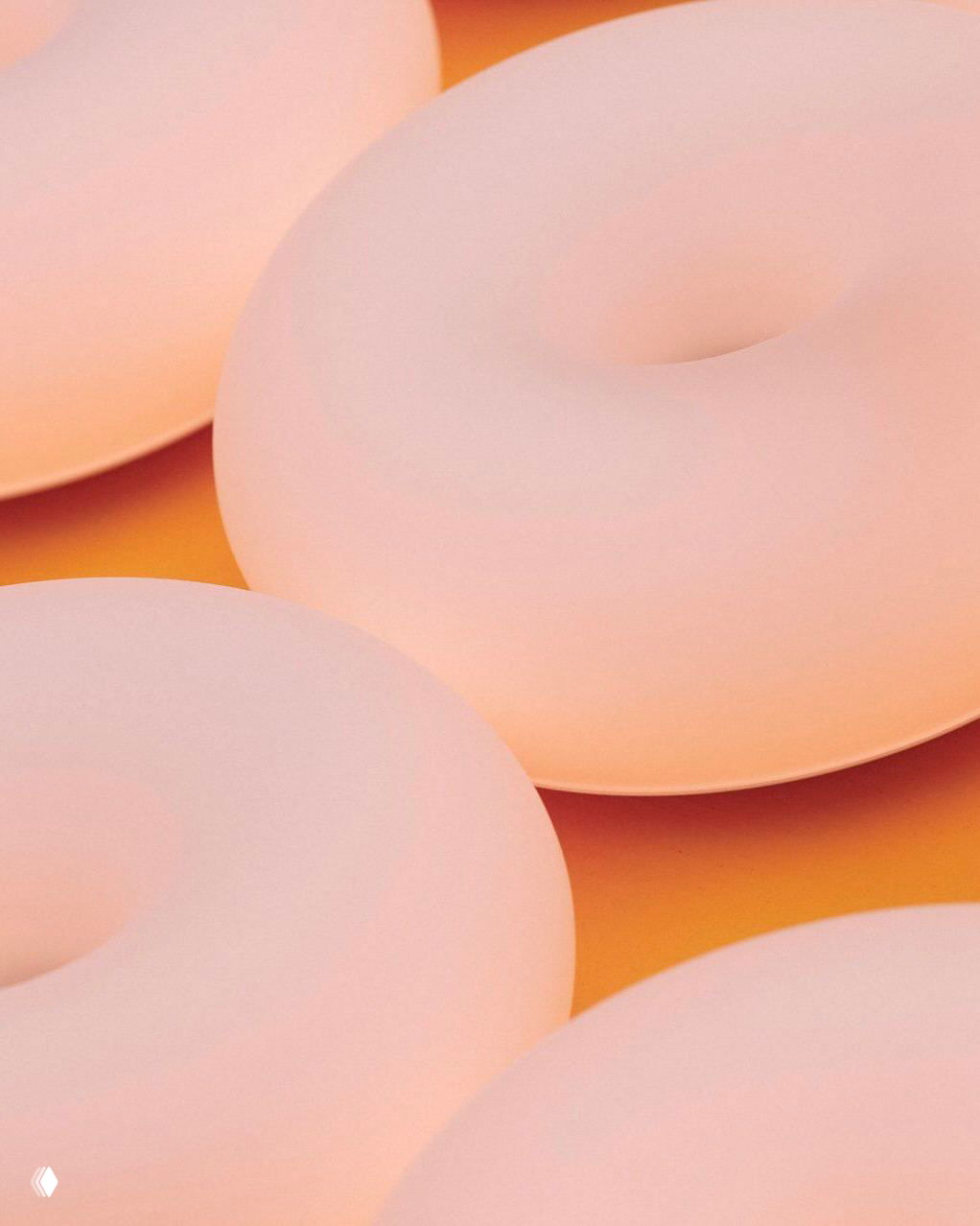 Крупный план матовых ламп‑пончиков с мягким внутренним свечением; видна гладкая белая поверхность и переходы тёплых нюансов света.