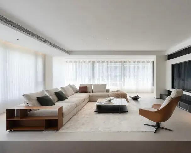 Светлый минималистичный интерьер с угловым модульным диваном Groundpiece, деревянные журнальные столики и кресло-качалка на переднем плане.