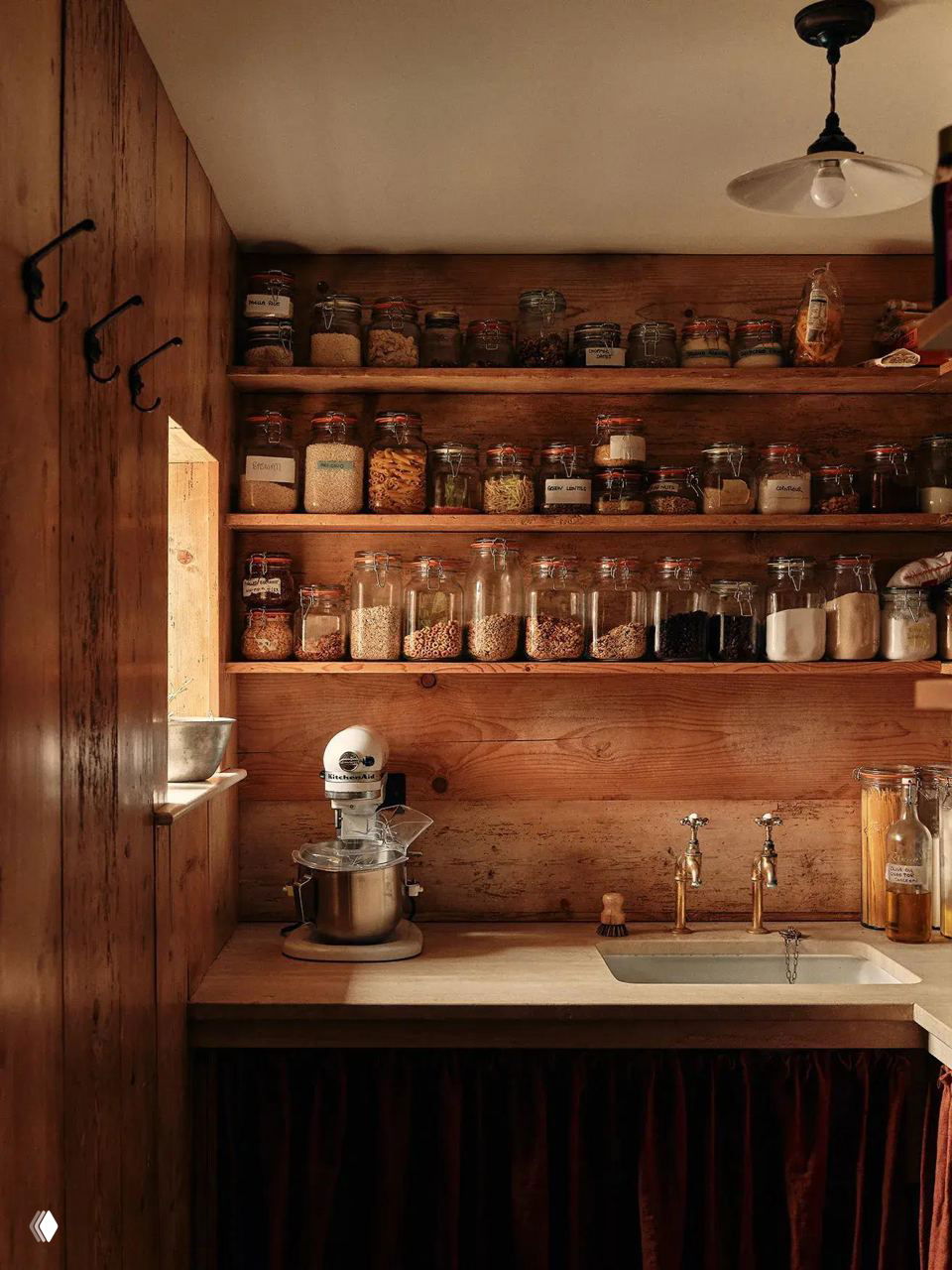 Уютная деревянная кладовая с полками до потолка, стеклянными банками и миксером на столешнице — тёплый стиль для хранения круп и специй.