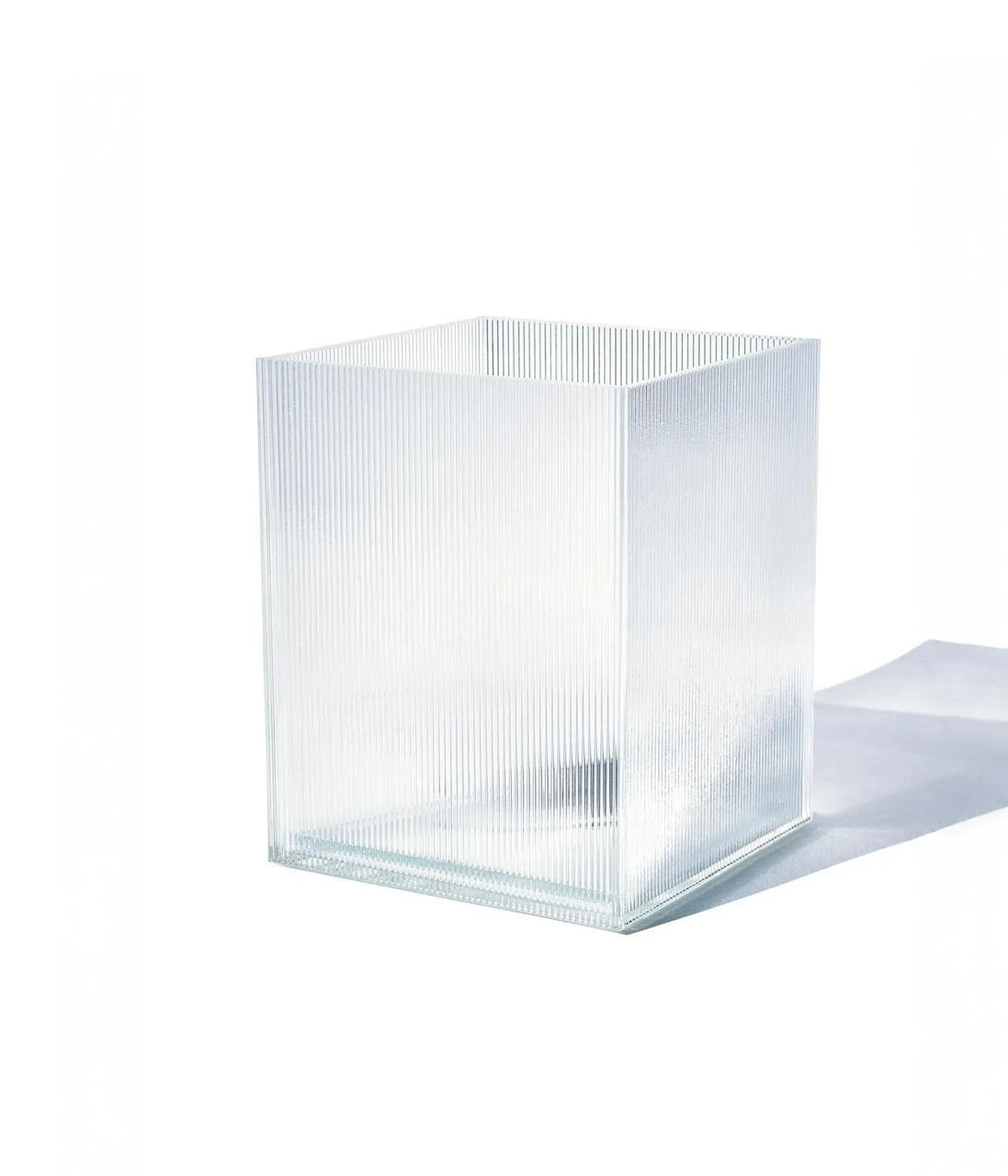 Прямоугольный прозрачный стеклянный куб с рифлёной поверхностью на белом фоне — минималистичный предмет дизайна из юбилейной коллекции Zara.