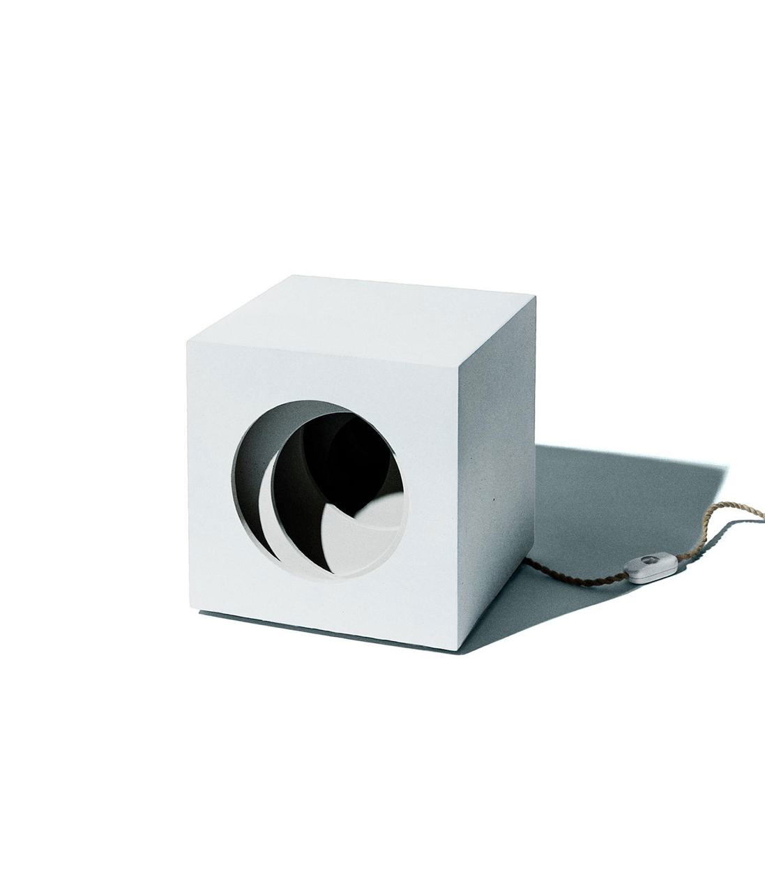 Белый куб с круглым отверстием и видимым шнуром на нейтральном фоне — интерьерный объект/светильник из лимитированной коллекции Zara.