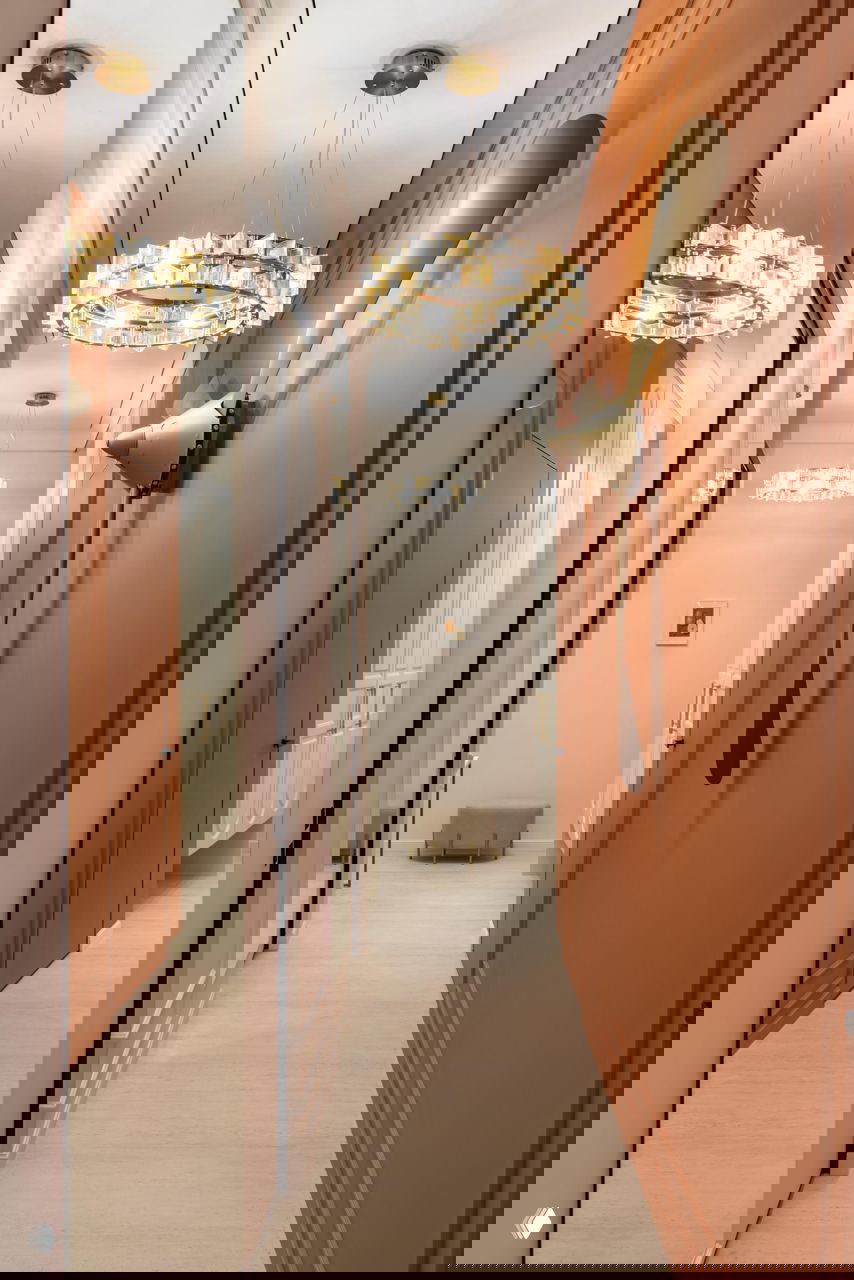 Прихожая-коридор в терракотовых тонах: декоративный винтажный авиационный пропеллер на стене и крупные зеркальные поверхности вдоль прохода.