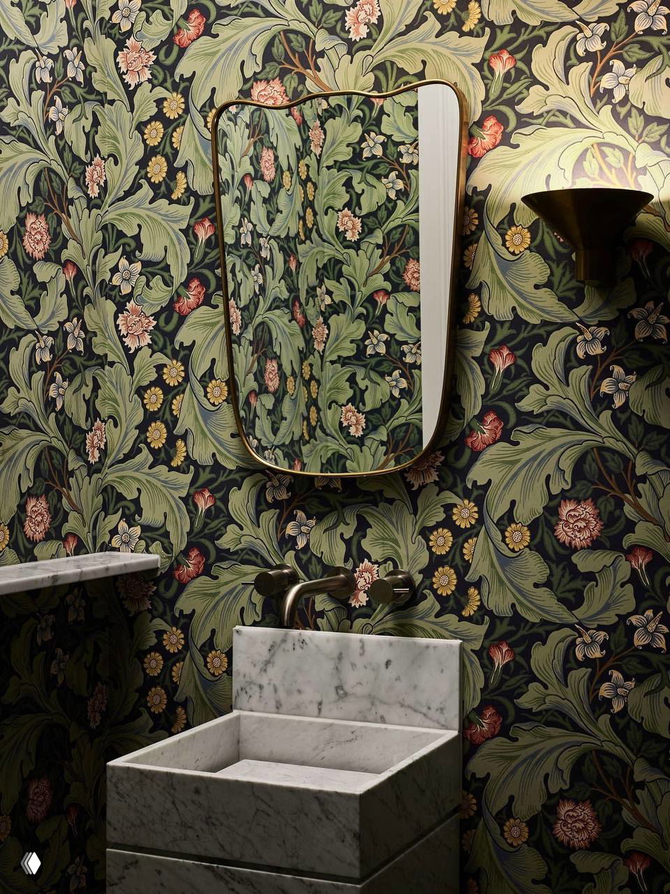 Обои в стиле Уильяма Морриса с богатым растительным орнаментом, зеркало в золотой раме и мраморная раковина на столешнице.
