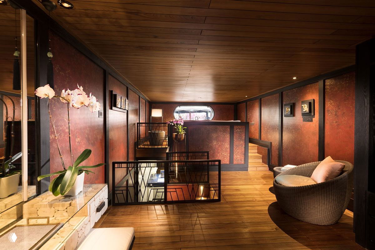 Внутренний переход и лестница на барже: тёплые деревянные панели, орхидеи у перил и декоративные панно в духе тайского ремесленного оформления интерьера.