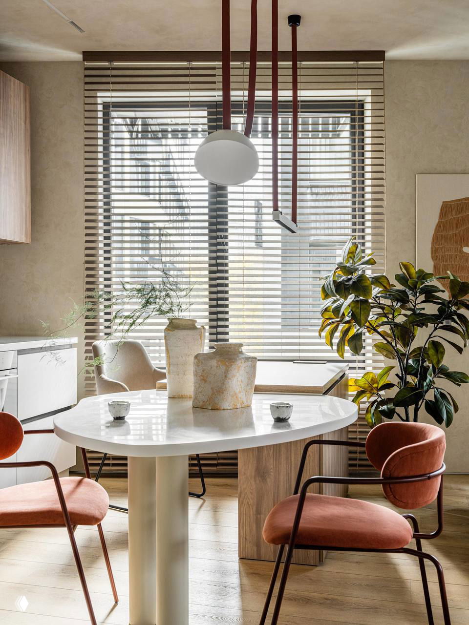 Обеденная зона с мраморным столом, терракотовыми стульями и крупными керамическими вазами на фоне большого окна с деревянными жалюзи и мягким светом.