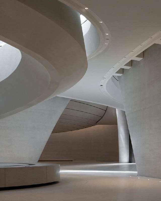 Интерьер музея: мягкие скруглённые бетонные формы атриума, чистые поверхности и рассеянный свет создают сдержанную современную атмосферу просветительского пространства.