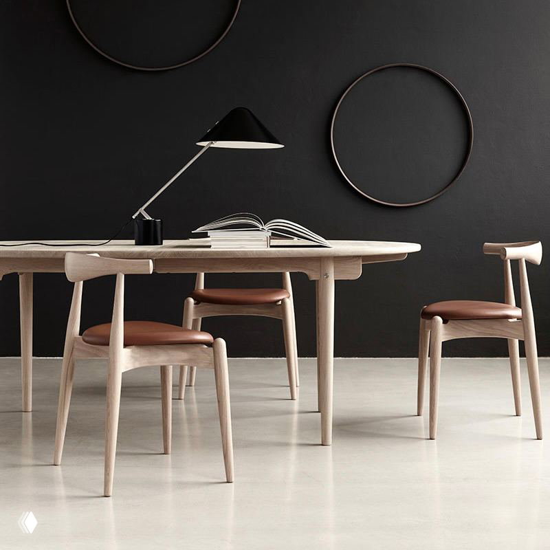 Современная интерьерная фотография: стол и набор светлых деревянных стульев с кожаными сиденьями на нейтральном фоне.