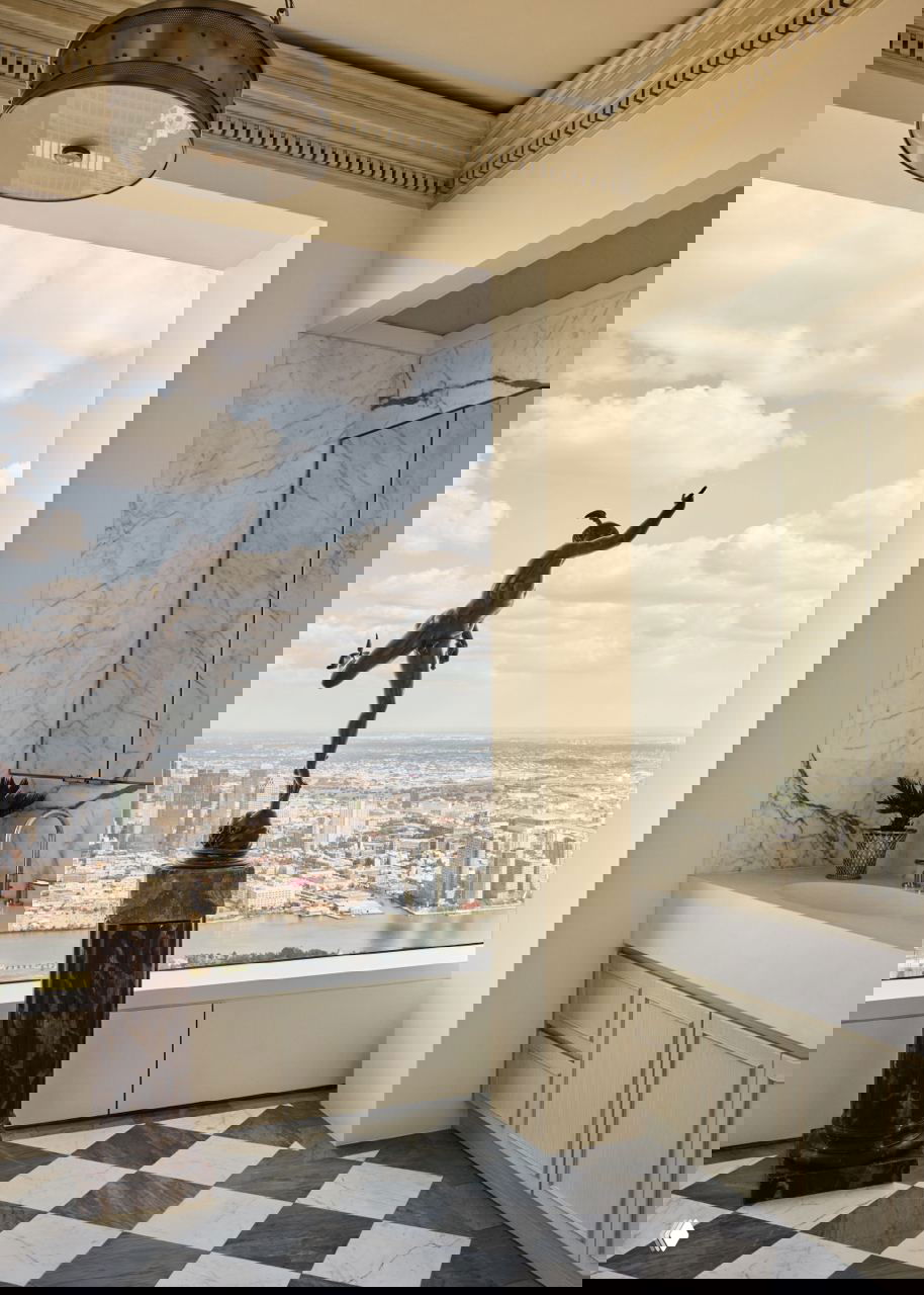 Санузел и зона с видом на Манхэттен: мраморные поверхности, графический пол и бронзовая скульптура у окна — контраст классики и городского пейзажа.