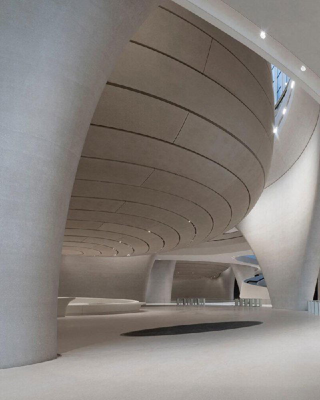 Объёмный зал с массивными монолитными колоннами и обтекаемыми линиями потолка; акцент на минималистичных формах и плавной геометрии интерьера музея.