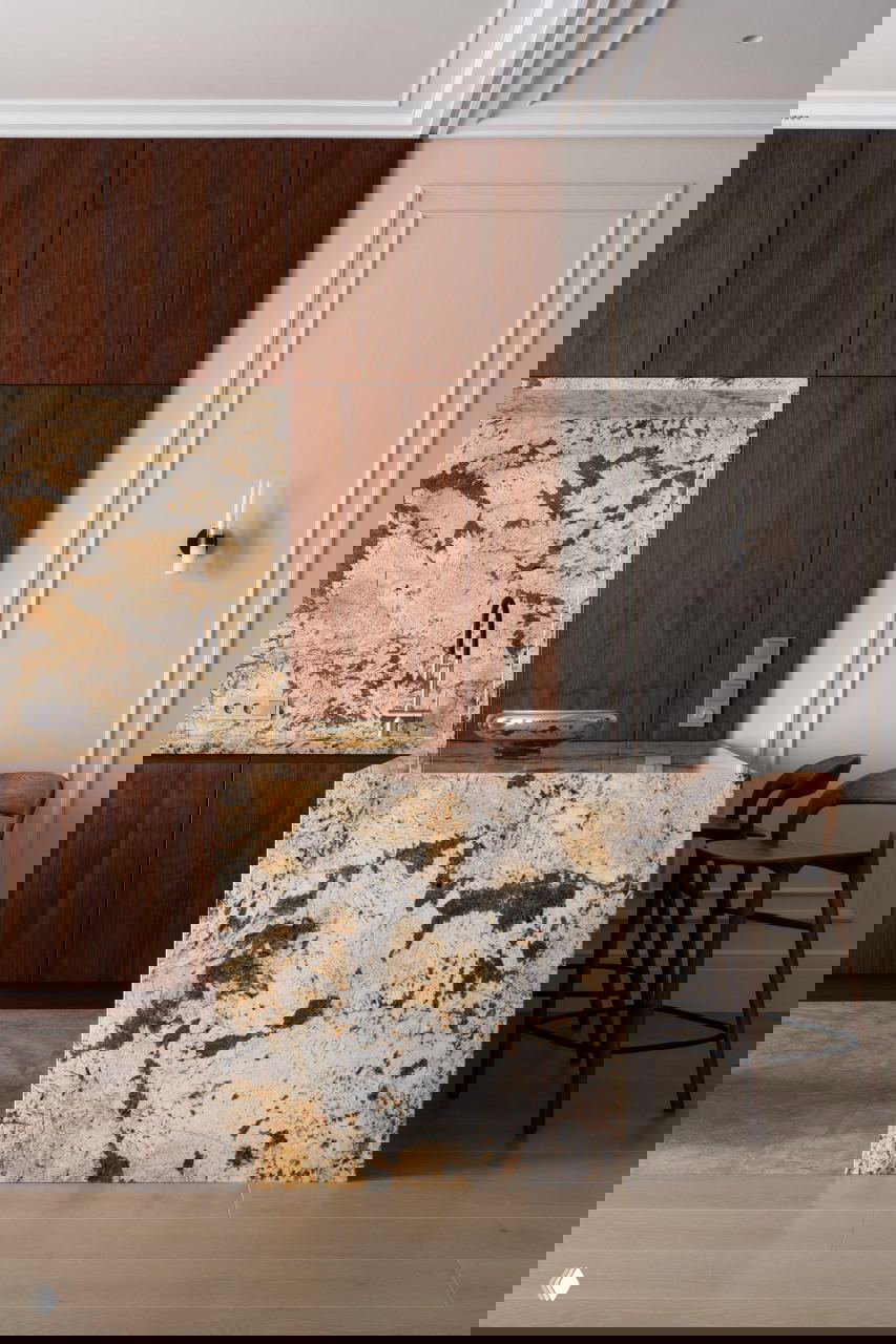 Кухонная зона с массивным мраморным островом и деревянными фасадами: тёплая палитра и выразительная текстура камня в интерьере квартиры 143 м².