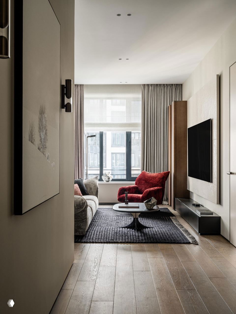 Гостиная с большими окнами, светлым диваном и акцентным бордовым креслом на фоне бежево‑серых стен и деревянного пола.