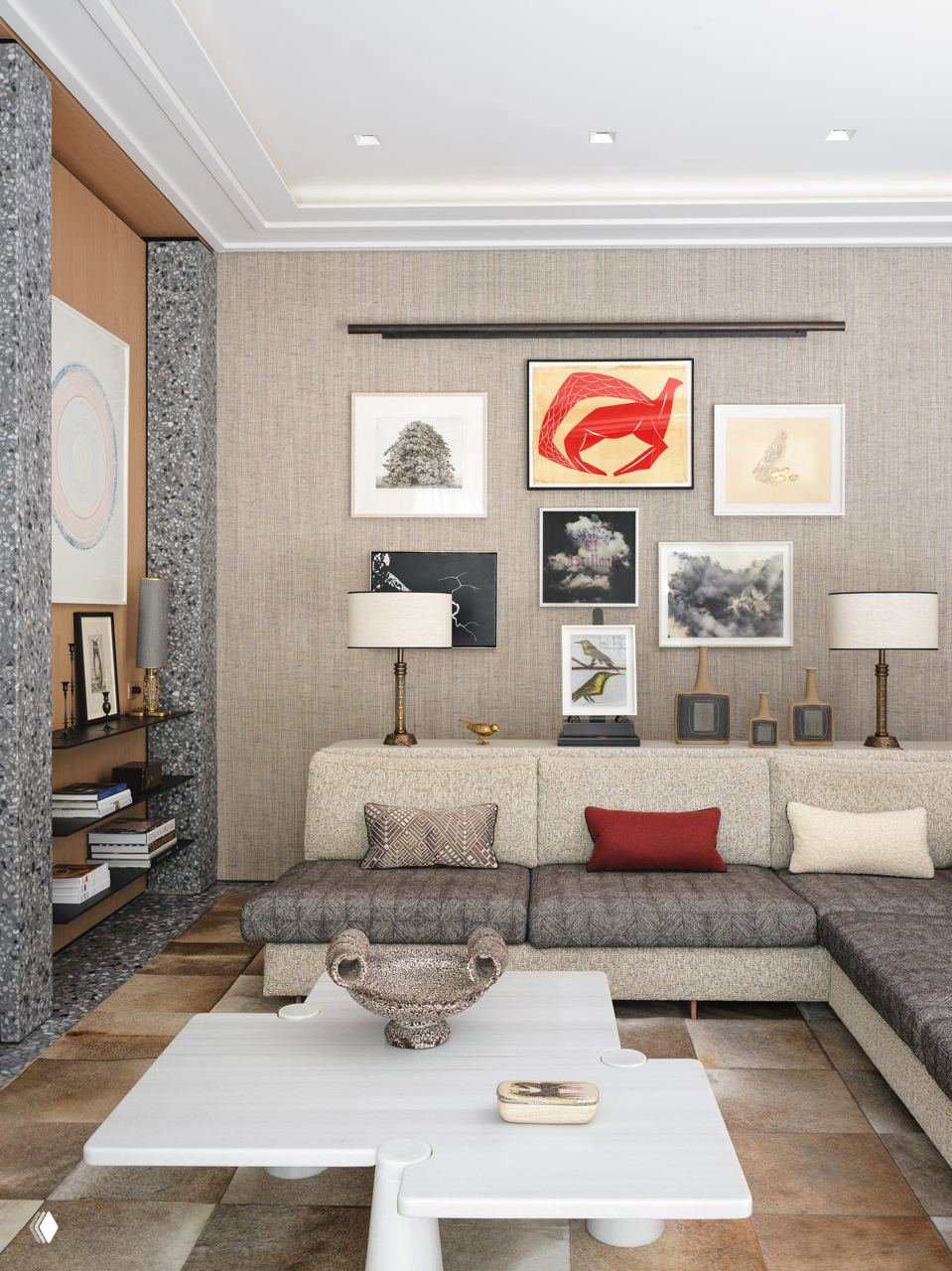 Гостиная с низким угловым диваном и галерейной стеной: несколько рамок с графикой и яркой центральной красной работой.