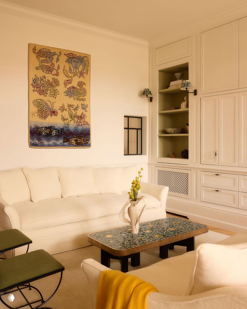 Гостиная с нейтральными стенами: светлый диван, настенный гобелен и керамический кофейный стол на светлом паркетном полу в спокойной цветовой палитре.