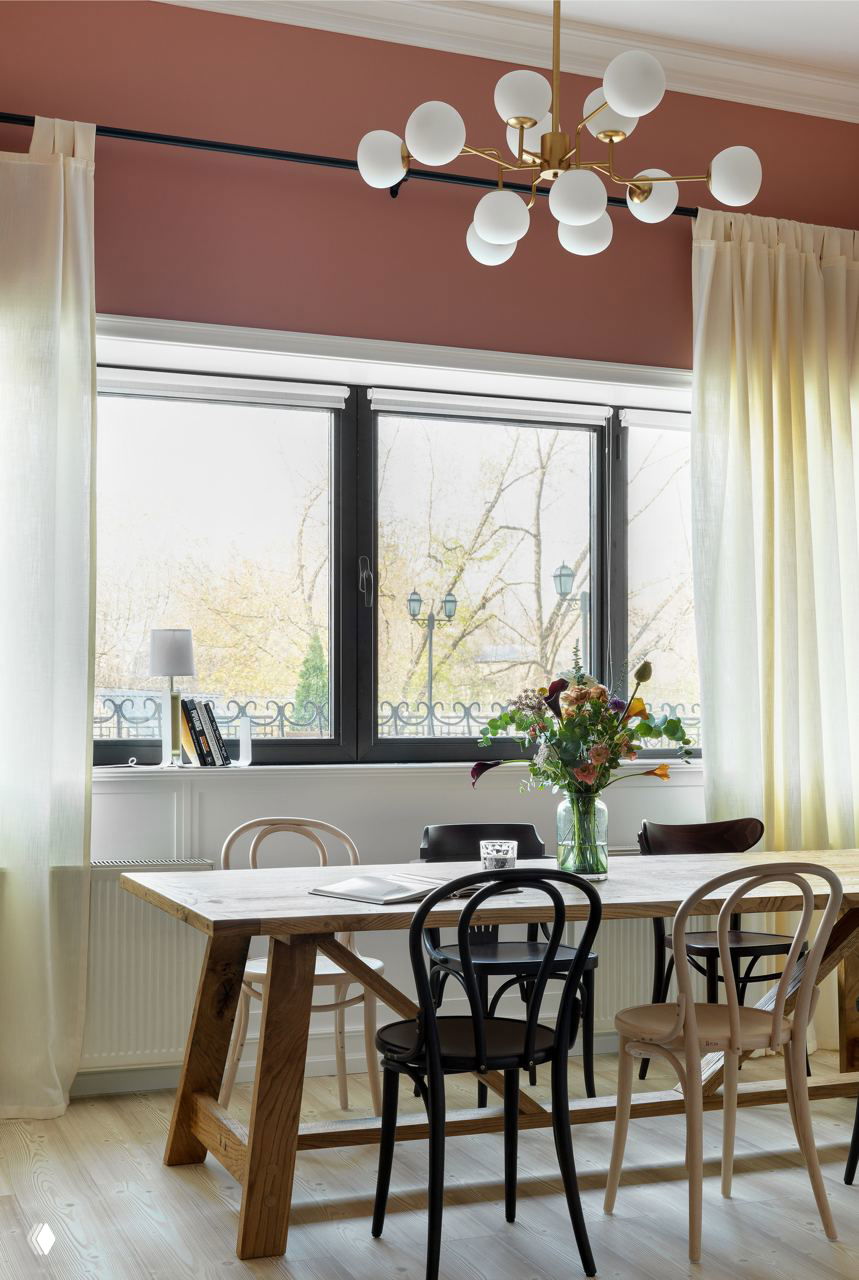 Светлая столовая с большим окном, венские стулья в черном и светлом дереве у простого деревянного стола и люстрой.