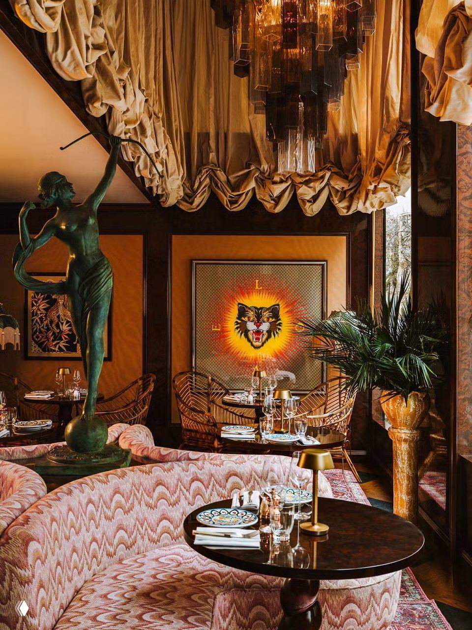 Уголок ресторана Gloria Ostería: полукруглый диван, бронзовая скульптура, декоративная картина с волком и роскошные текстильные драпировки.