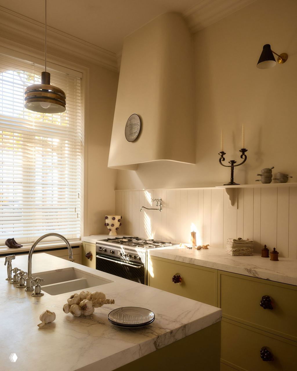 Кухня со встроенной вытяжкой: мраморная столешница, раковина, газовая плита и оливковые кухонные шкафы при большом окне с жалюзи.