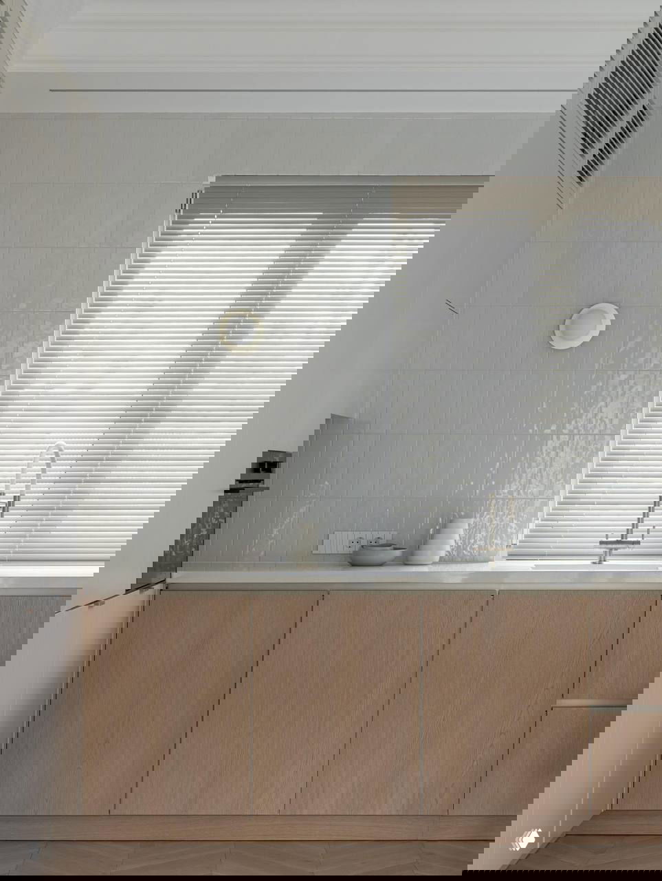 Кухонная зона с светлой плиточной стеной, деревянными нижними шкафами и монохромной столешницей у окна, лаконичная встроенная техника.