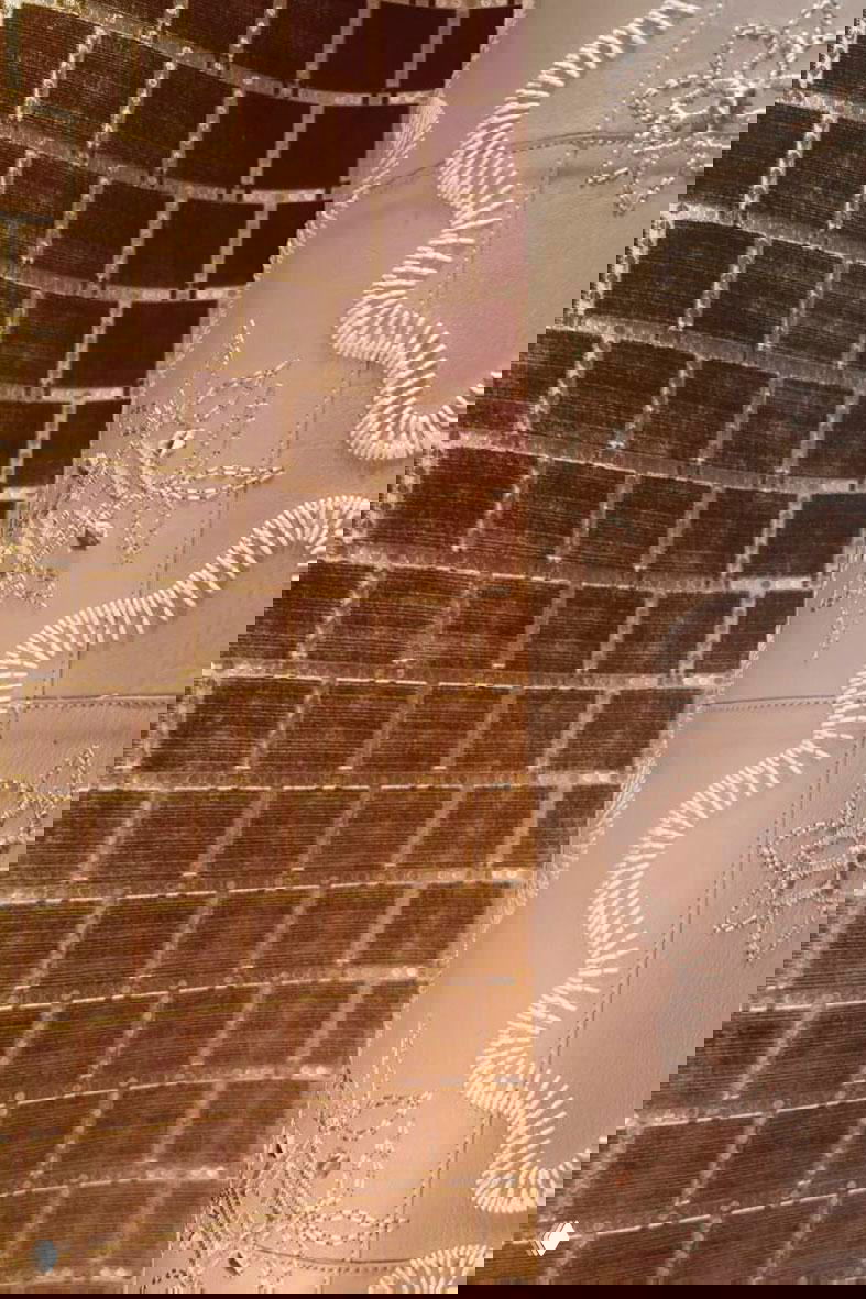 Текстильные панели с вышивкой и фактурной отделкой рядом с тканями в клетчатых и кирпичных узорах, тёплая гамма.