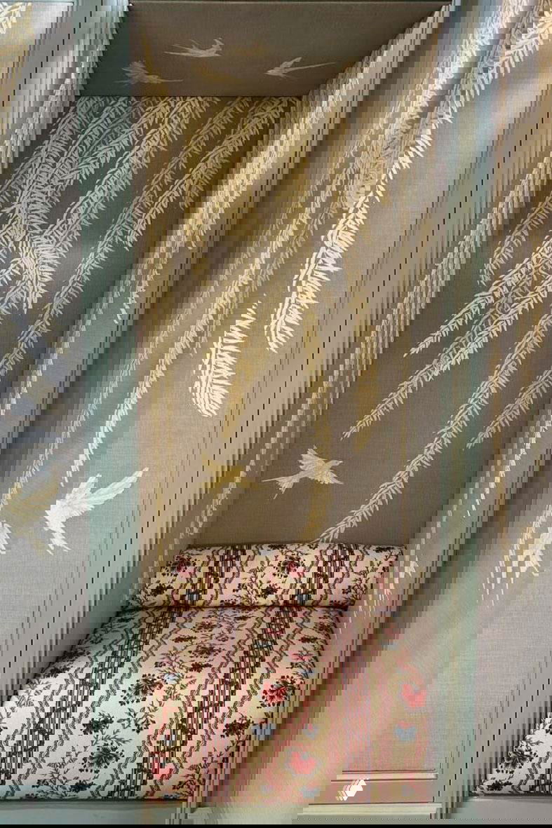 Шинуазри-панель с изображением ив и летающих птиц, встроенная ниша с сиденьем, отделанным полосатой и цветочной тканью.