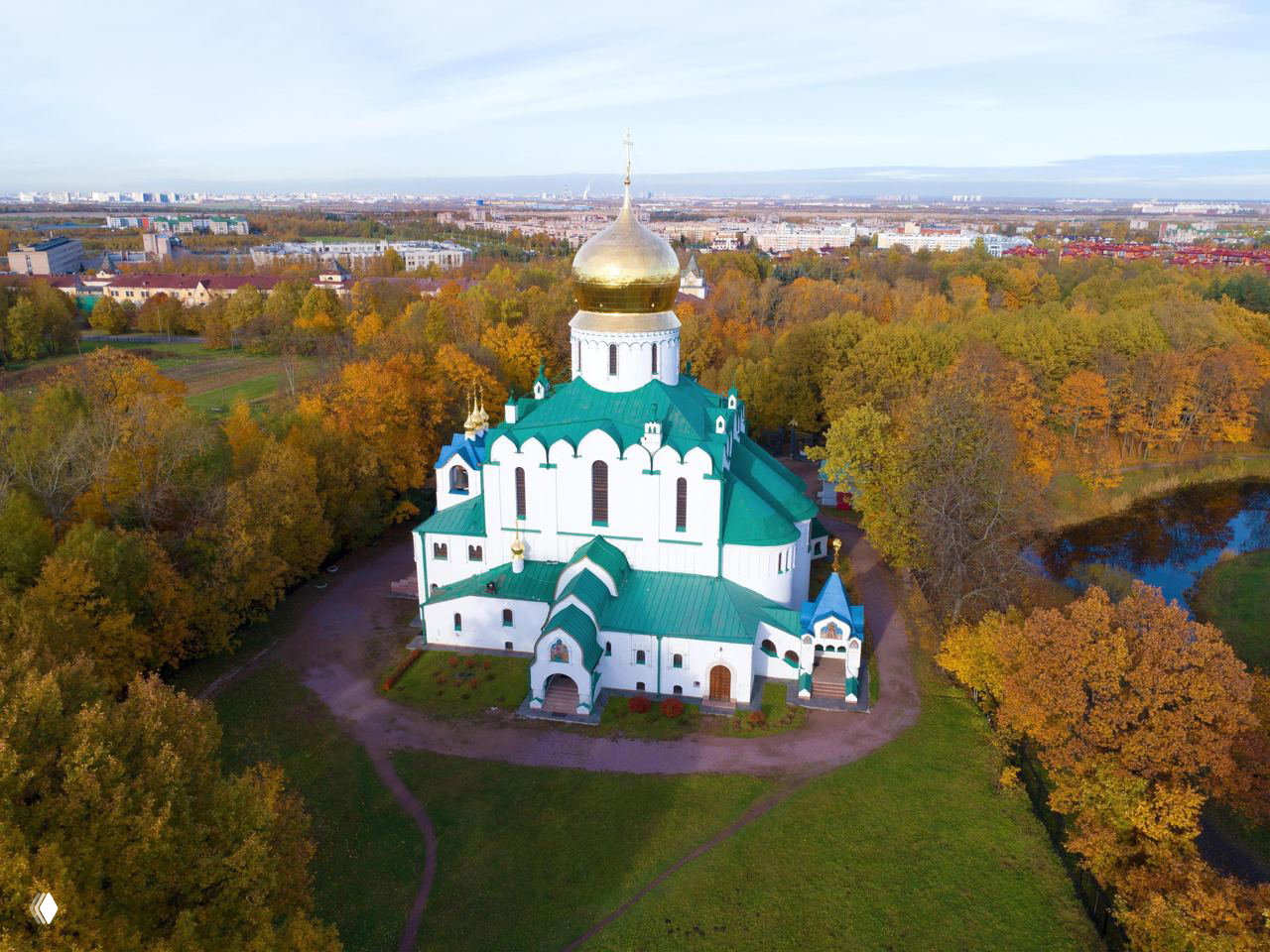Феодоровский собор в Царском Селе с золотым куполом и зелёной кровлей, окружённый осенним парком, вид с высоты.
