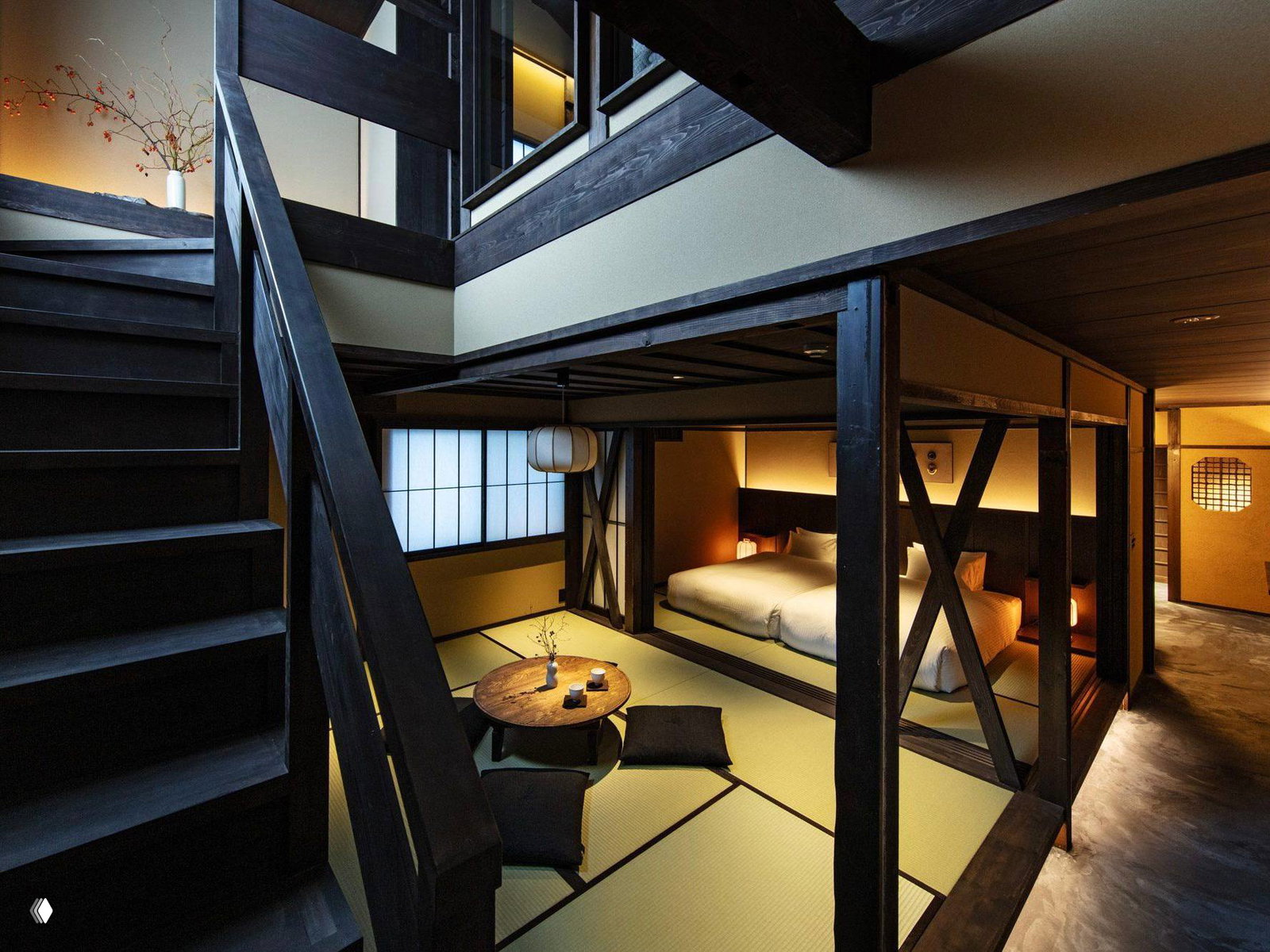 Интерьер номера с деревянной лестницей, татами и низким столиком; вид на зону с футоном и мягким освещением в реконструированной матии