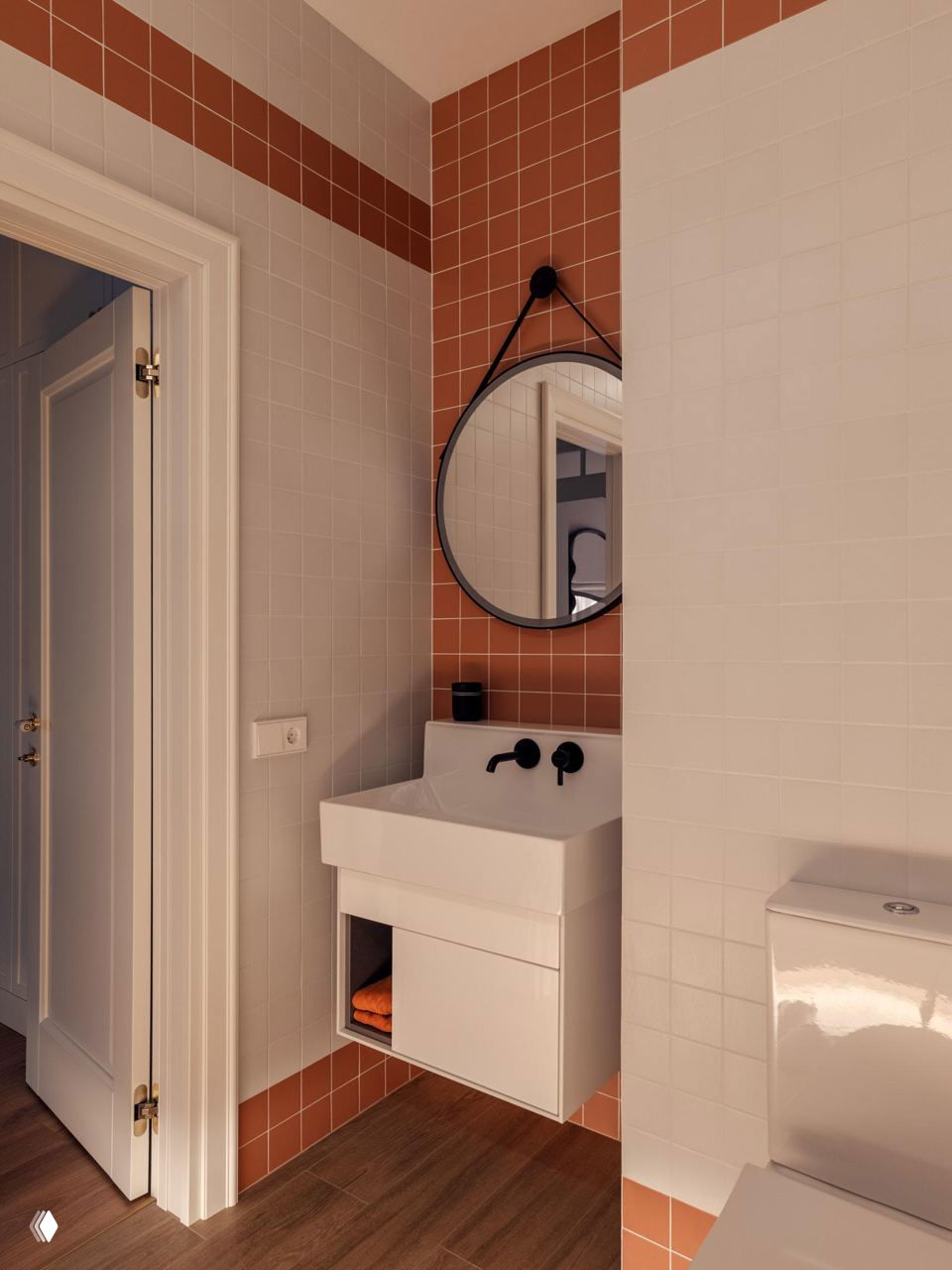 Небольшая ванная с белой раковиной, круглым зеркалом и полосой терракотовой плитки — компактный санузел в единой тёплой гамме материалов.