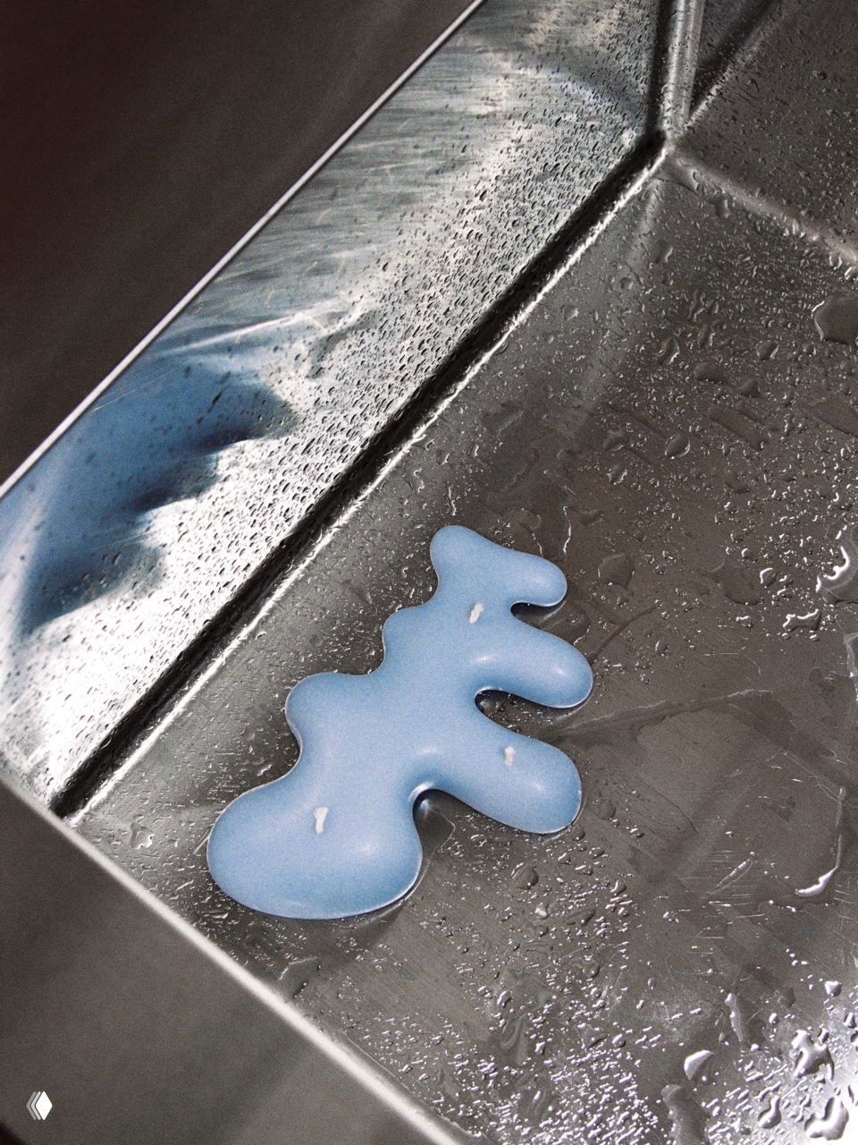 Кусок расплавленной синей свечи на металлической поверхности — художественная фотография, подчёркивающая взаимодействие воска и отражающей стали в работах .dpt.