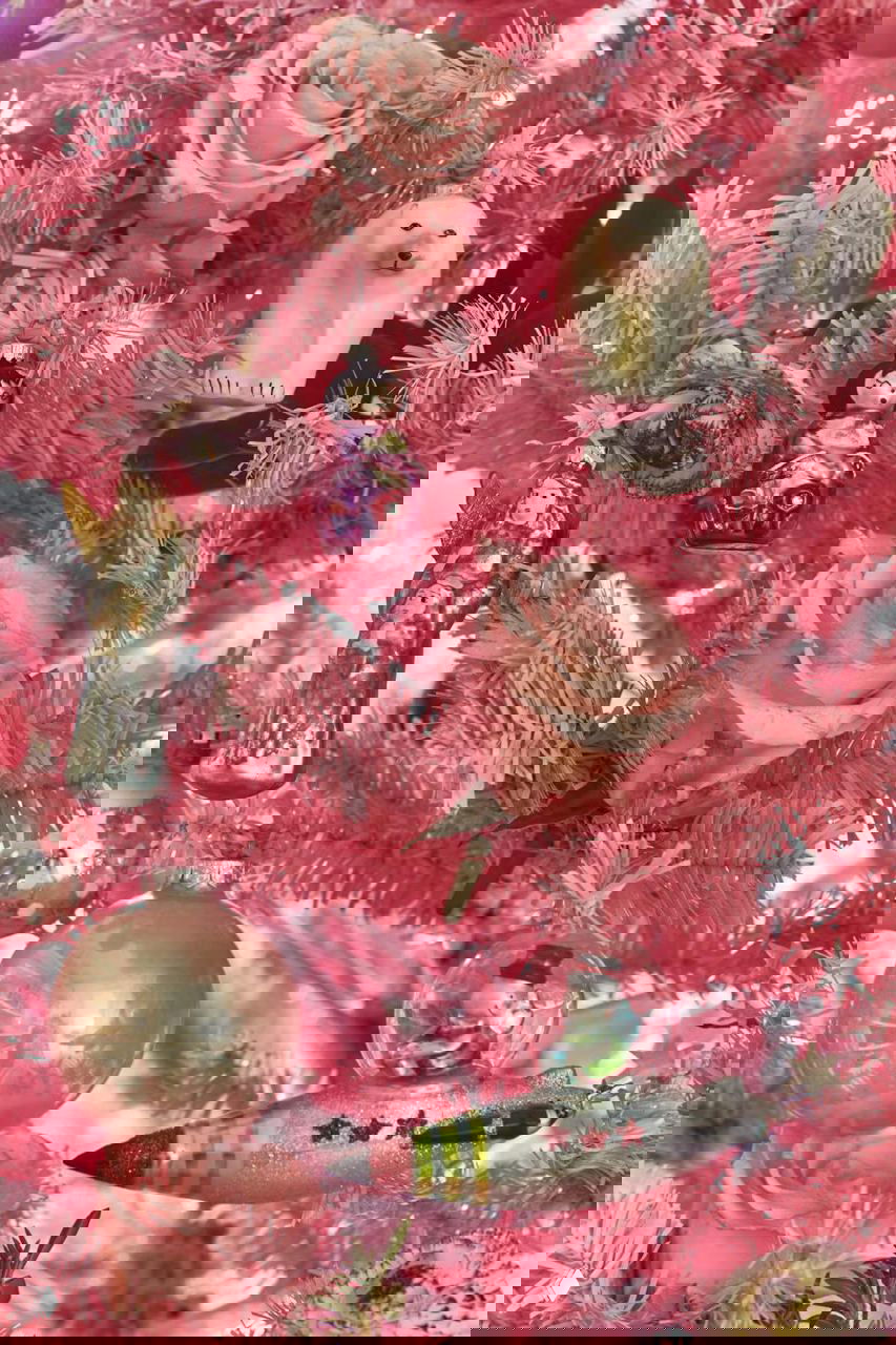 Крупный план розовой елки с различными стеклянными игрушками со всего мира, засушенными розами и зеленью, детально видны винтажные и авторские украшения