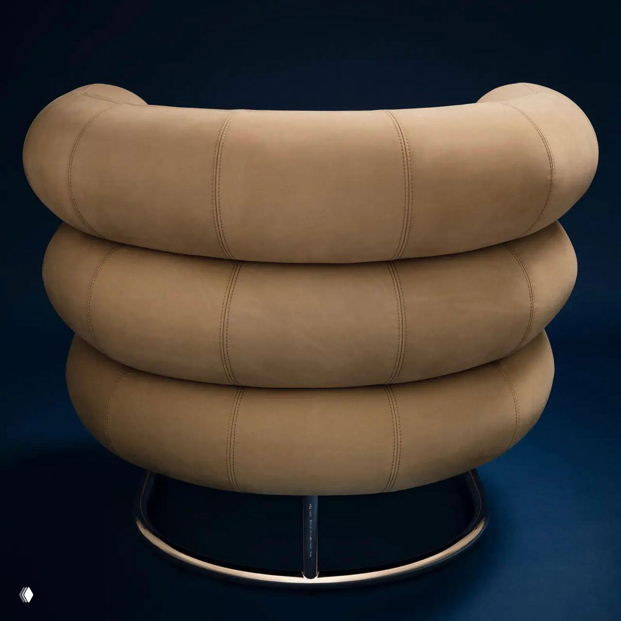 Крупный план задней части кресла Bibendum: три слоя цилиндрических валиков в золотистой нубуковой коже с видимыми строчками и хромированным основанием на тёмном фоне.
