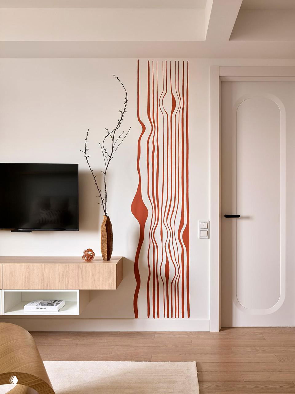 Фрагмент стены с телевизором и авторской настенной росписью терракотового цвета в виде плавных вертикальных линий, рядом деревянная консоль.