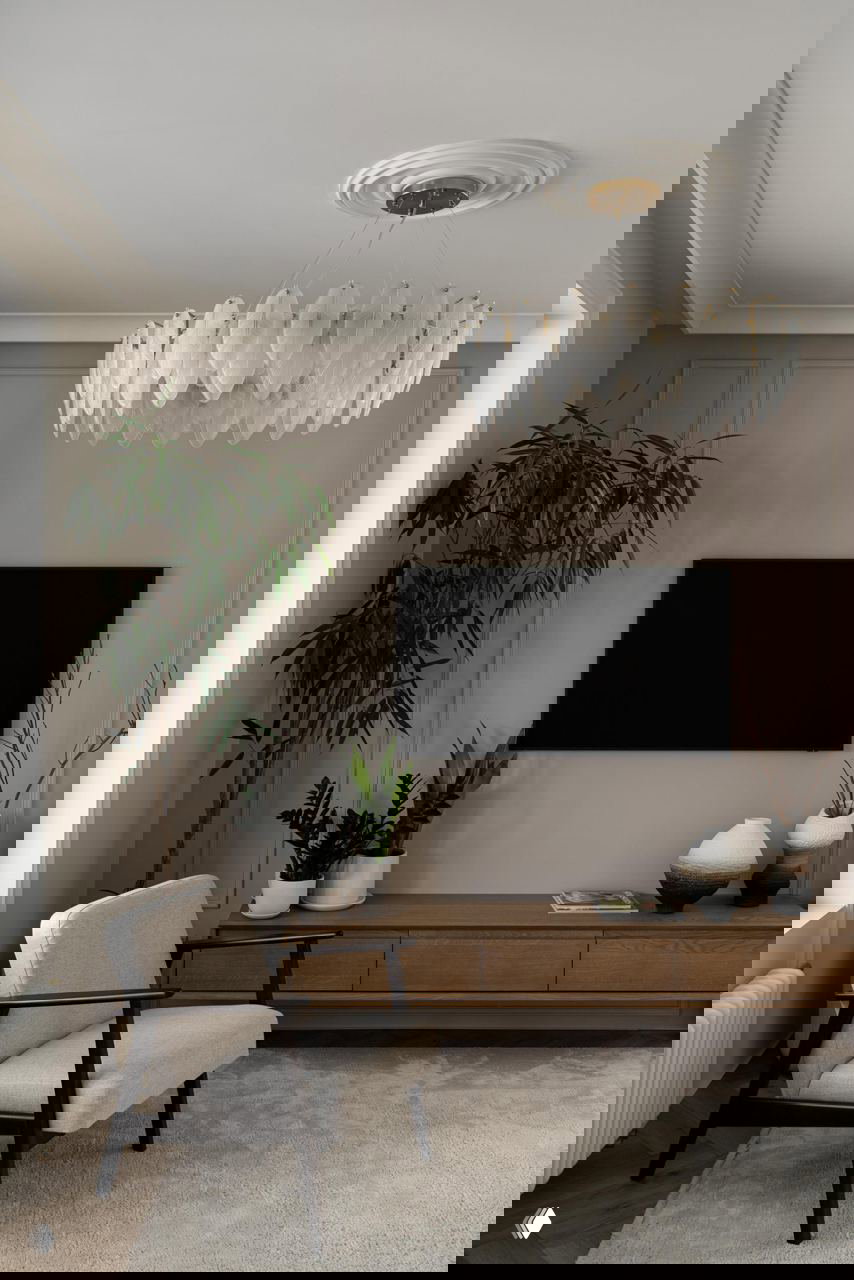 Гостиная с низкой тумбой из натурального дерева, светлым креслом и эффектной люстрой: спокойная гамма, текстура дерева и мягкие формы в интерьере.