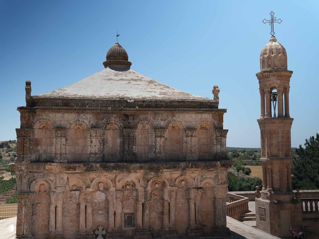 Фрагмент фасада древней церковной постройки IV–V веков в Анытлы: резные арки, рельефы и купол с крестом на верхушке.