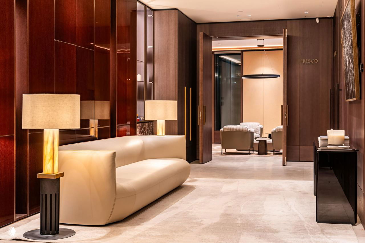 Коридор и переговорные: кожаный диван на фоне тёмных деревянных панелей и вход в приватные комнаты с подсветкой.