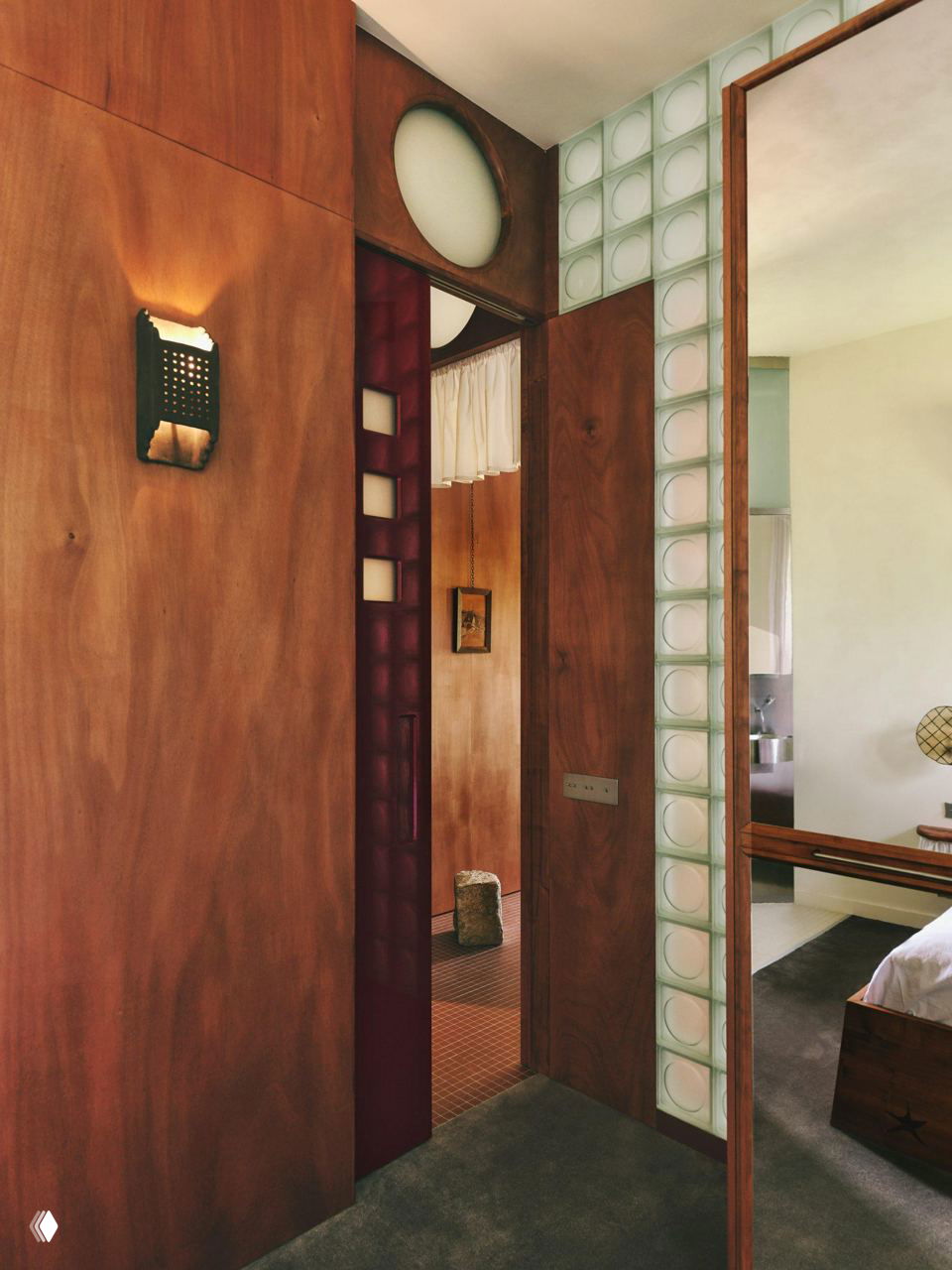 Проход между помещениями: деревянные перегородки, стеклоблоки в дверном проёме и вид в спальню с мягким естественным освещением.