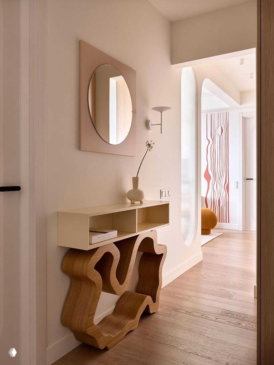 Прихожая с декоративной консолью необычной формы из рифленого дерева, овальным зеркалом и аккуратными пастельными акцентами в отделке.