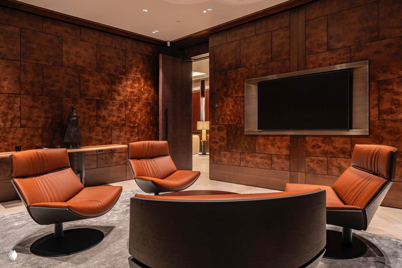 Лаунж-зона: кожаные кресла терракотового цвета, круглый стол и стены с тёмной фактурой — яхтенная эстетика интерьера.