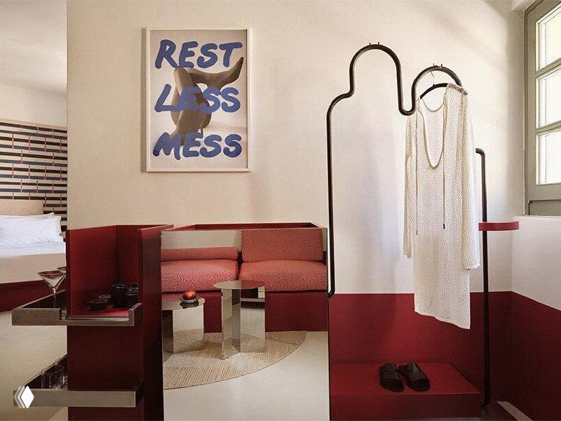 Угол номера с постером «REST LESS MESS», зеркальными поверхностями, красными мебельными вставками, открытой вешалкой и дизайнерской отделкой
