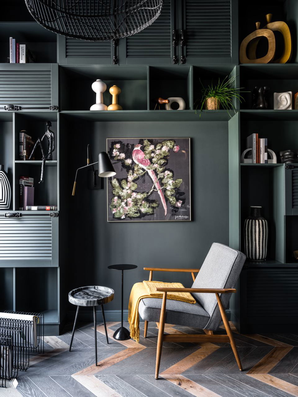 Современный тёмный стеллаж с декоративными объектами и лёгким креслом: сочетание графичности и уюта в зоне для чтения.