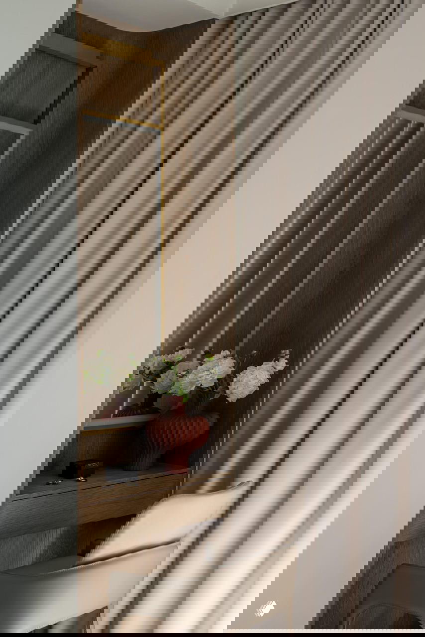 Уголок с гримерным столиком и зеркалом в деревянной обшивке, плотные шторы и сдержанная цветовая палитра — элементы скандинавского характера в неоклассическом пространстве.